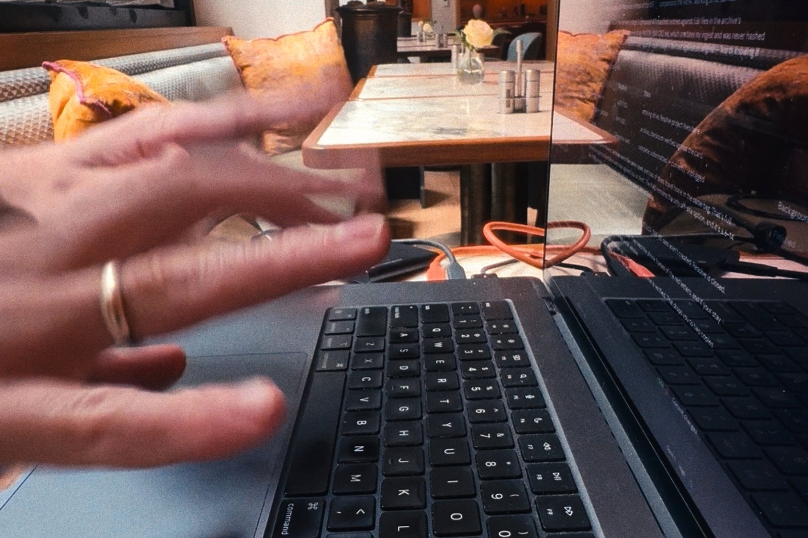 Hands typing on a laptop at a restaurant table